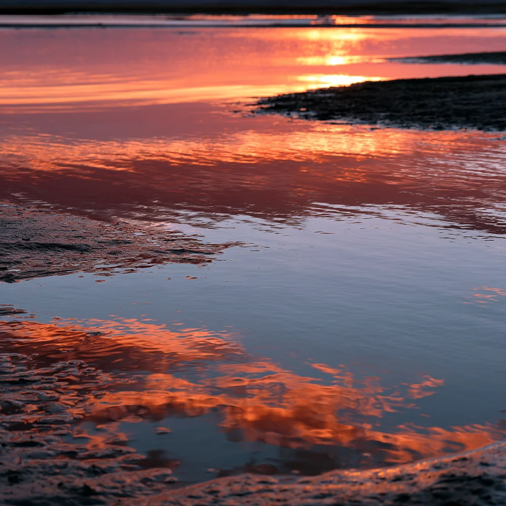 A tide pool held between wet rock at low light.